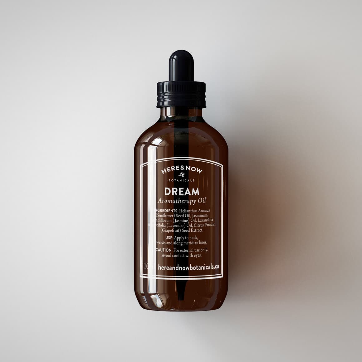 Mockup of amber bottle logo design for Here & Now, an aromatherapy oil botanical brand.