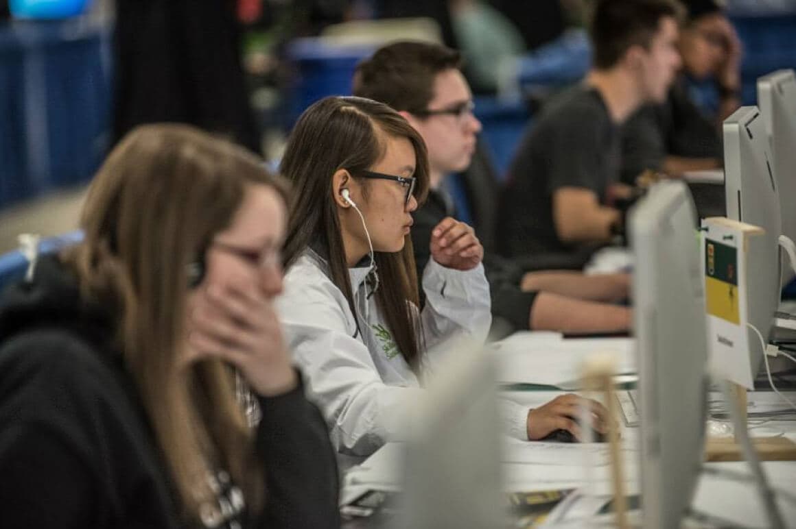 Event photo of 5 student competitors concentrating while looking at their computer screens during the Graphic Design competition.