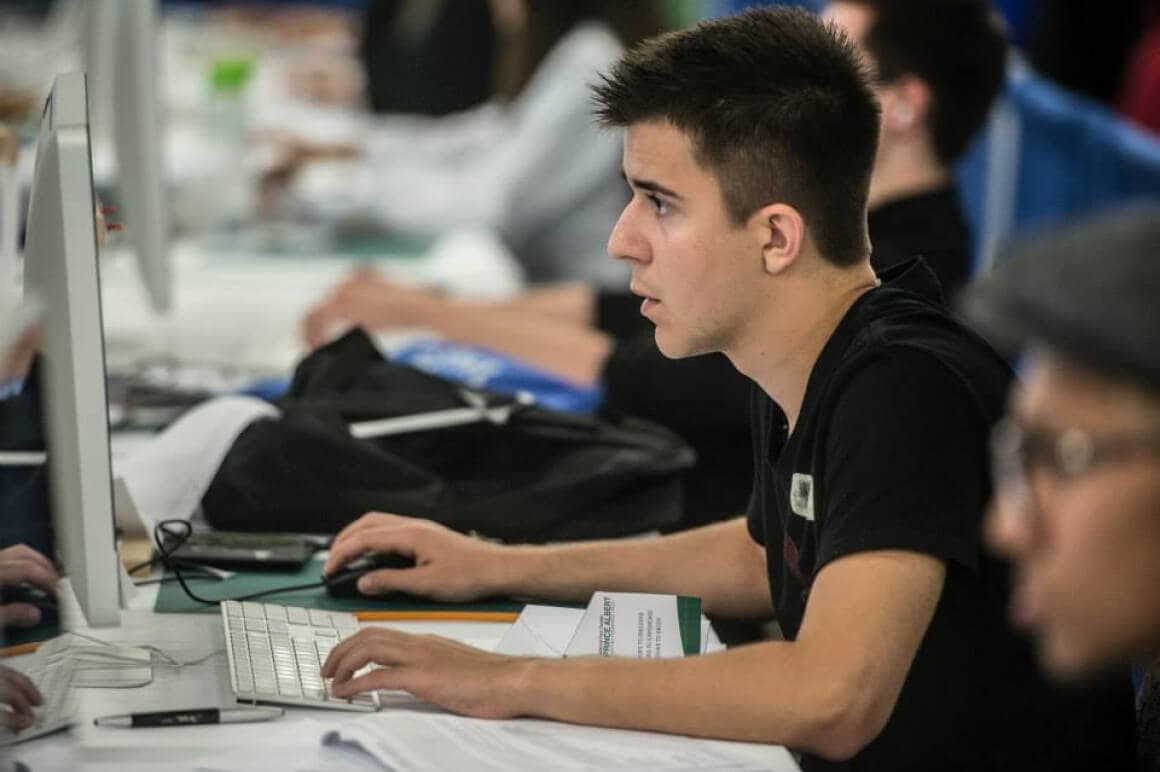 Event photo of 4 student competitors concentrating while looking at their computer screens during the Graphic Design competition.